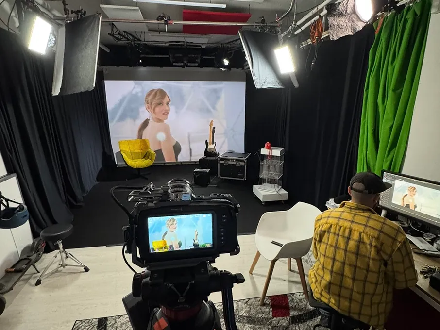 Set dello studio con camera in regia rivolta verso il LED Wall acceso: poltrona gialla, chitarra e monitor di ripresa